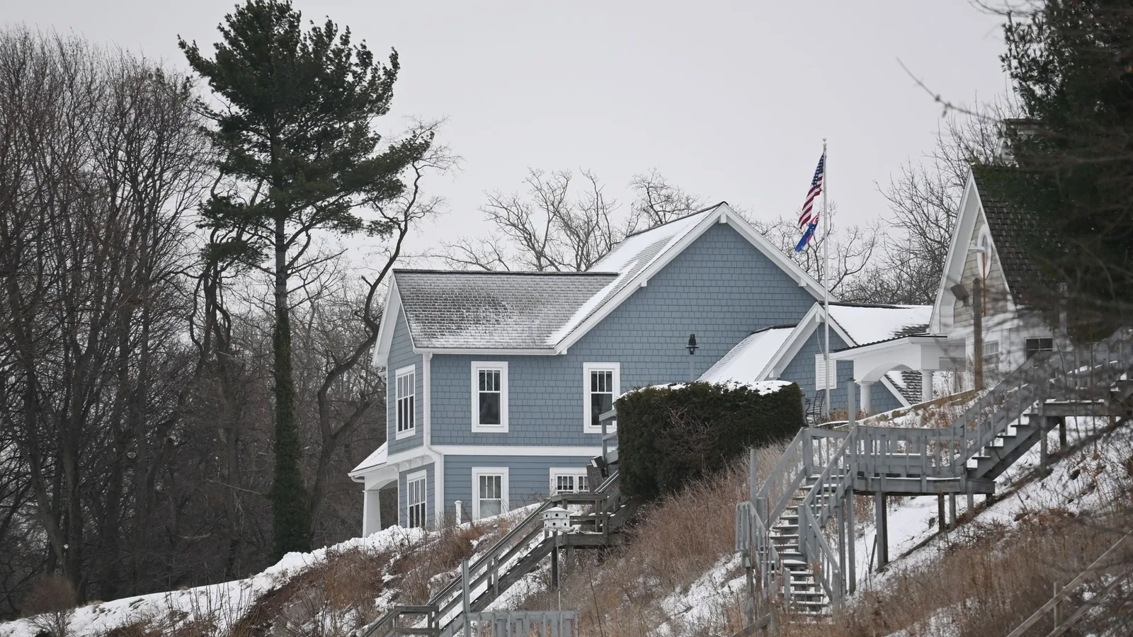 Two-story blue house on a snowy hillside, the kind of cold climate home a DIY mini split heat pump has to carry through winter