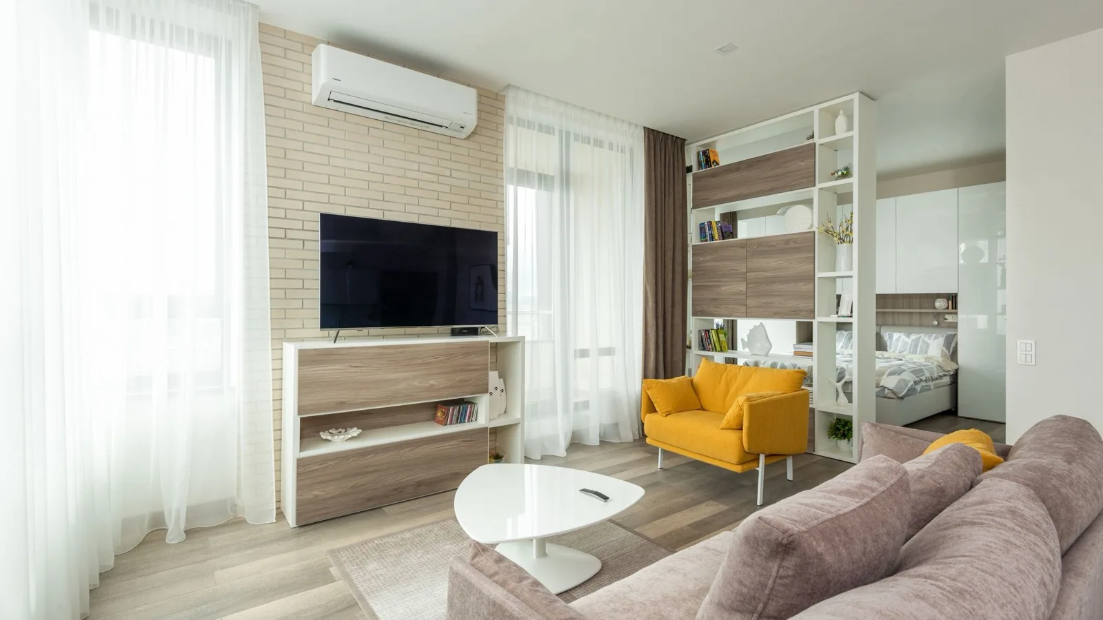 Studio apartment living area with a white wall-mounted mini split head above the TV, about the size of space a DIY mini split for 500 square feet serves