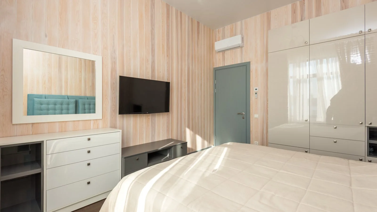 Sunlit bedroom with a white wall-mounted mini split head above the door, the kind of second room an easy install dual zone mini split can serve