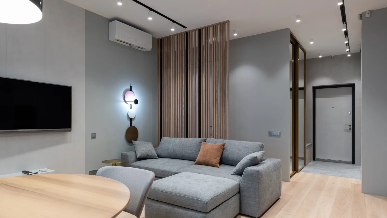 Open-plan living room with a white wall-mounted mini split head above the TV wall, one zone of a pre-charged multi zone mini split system