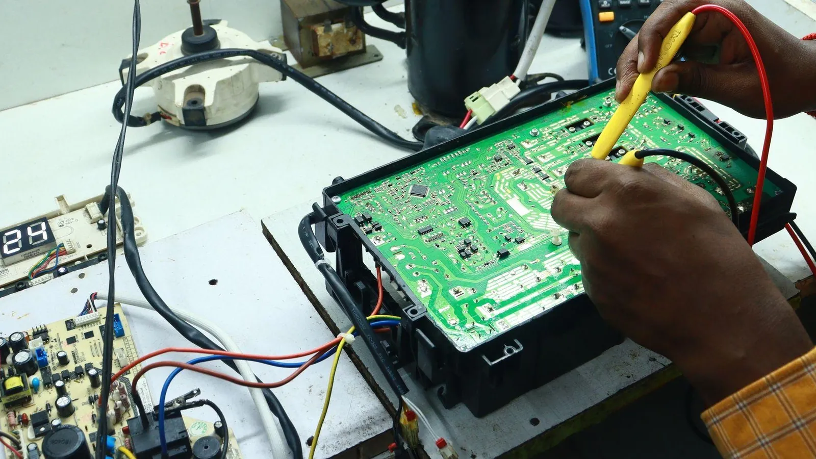 Technician testing HVAC circuit board with multimeter to fix mini split communication error